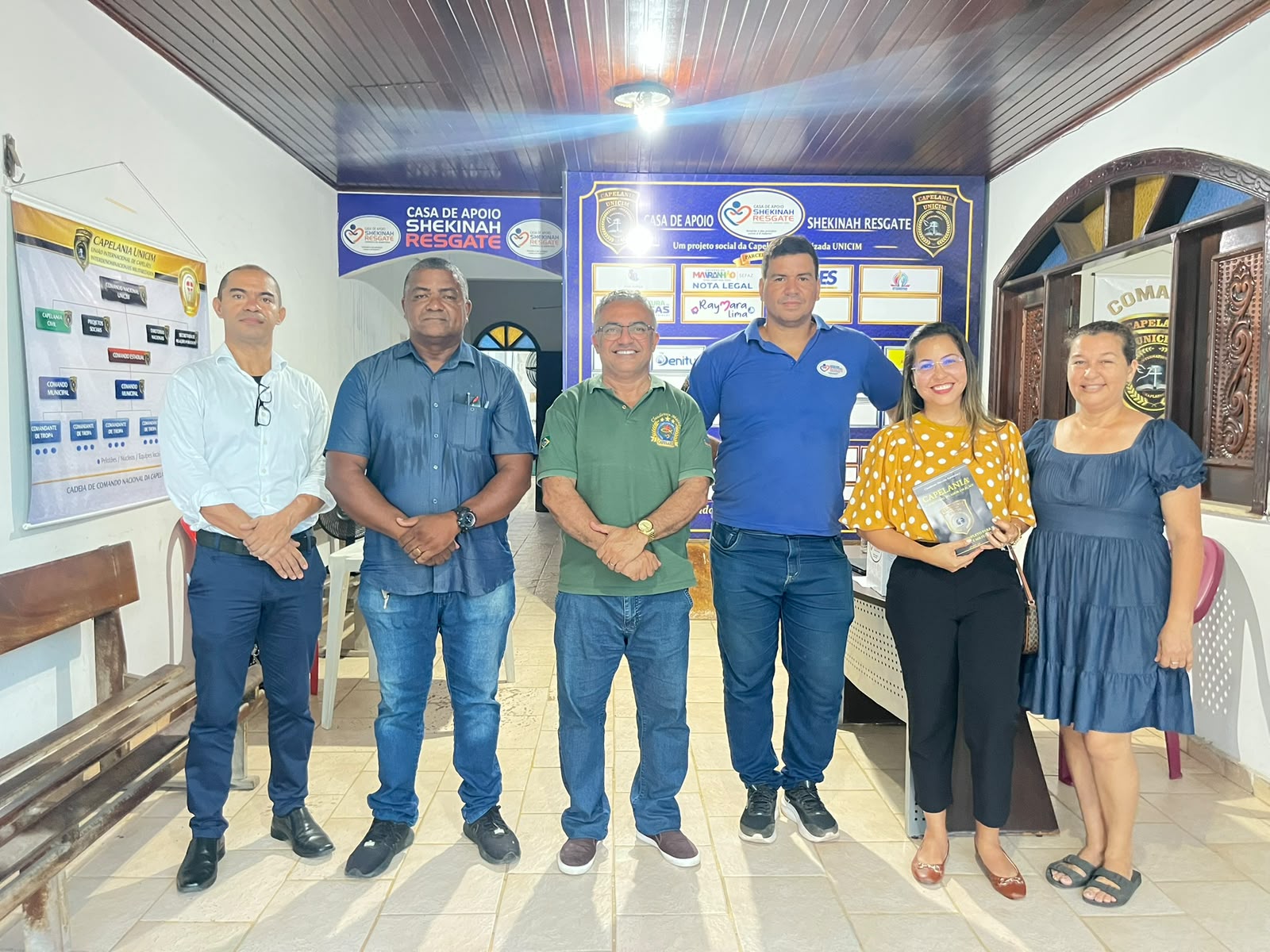 Equipe reunida na sede da Casa de Apoio Shekinah Resgate com o livro